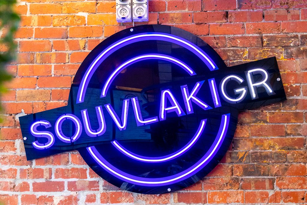 Souvlaki GR neon sign on a brick wall